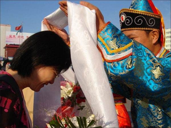 Hình ảnh một bậc Đạo sư đang mỉm cười hiền từ, choàng chiếc khăn Khata trắng lên vai một vị khách hoặc người tu tập đang chắp tay thành kính.